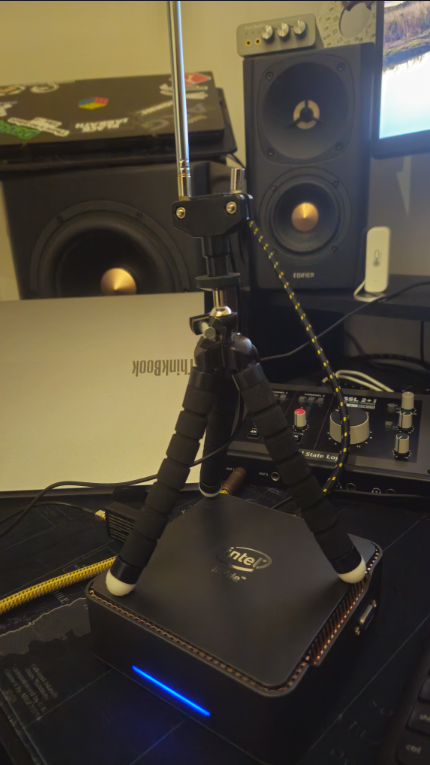 Mini PC do homelab com o tripé flexível do kit montado sobre o gabinete e a antena estendida na vertical
